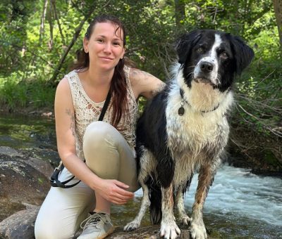 photo d'un humain et de son chien en balade prêt d'un rivière